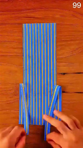 Hands fold striped fabric on wooden surface