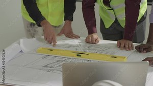 Close-up, Engineers, construction workers, and contractors look at a paper plan of the building.