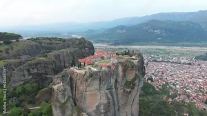 Meteora: Holy Site In Greece (Location Shot). Aerial Approach Towards Monastery Floating On Rock Pillars Above The City.