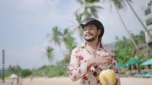 Outgoing individual enjoys tropical beach, sips fresh coconut in cowboy attire. Confident LGBTQ person with styled mustache relaxes by ocean. Gay traveler on sandy shore embodies freedom, pride.