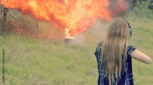 A huge explosion after a woman fires her weapon and hits an explosive target, slow motion 24fps.