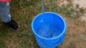 Unrecognizable person pouring water into empty bucket.