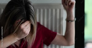 Crying and scared woman handcuffed to heating radiator