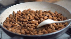 Close-up, the process of frying and stirring almonds nuts in a pan on the stove, vegetarian, healthy food, diet, cooking, time lapse, 4x speed