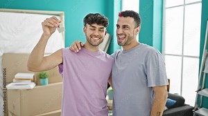 Two men couple hugging each other holding keys at new home