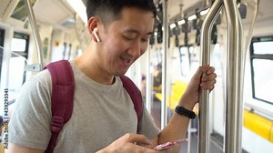 Close up of young man listening to music with wireless earpods and using mobile phone while commuting by train. Asian guy enjoying music on the go. Stock Video