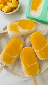 With only 3 ingredients, these mango ice pops are an easy homemade idea for the summer. Perfect for a simple treat. They are made with blended mangoes (with a bit of lime juice) and coconut milk. I used the thick creamy part at the top of the can (it looks runny in the video as it was so hot here when I made them!). Full recipe on helenridgeway.com #icepops #icelollies #mango #summerrecipes | Helen Ridgeway Nutrition