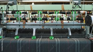 weaving looms. weaving factory. textile industry. Close-up. Automated weaving machine is fabricating cloth of threads. Textile factory equipment. fabric production.