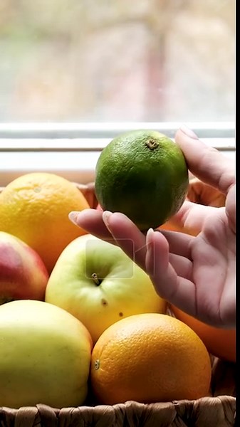Woven basket on windowsill holds grapefruit, apples, orange, lime. Girl touches and inspects fruits. Early spring outdoors, reminder to get enough vitamins Stock Video Footage - Alamy