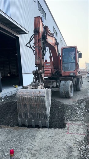 Excavator digging trench to install rain pipe through road