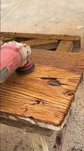 sanding and smoothing a weathered wooden plank surface with a power orbital sander to restore it