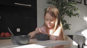 Cute teenage girl sits at the dinner table and eating porridge for breakfast. Healthy lifestyle concept.