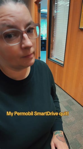 Text overlay: My Permobil SmartDrive quit! ID: Joy is a white woman with brown hair, pulled back into a bun. She is wearing glasses and a black sweatshirt and black sweatpants. She is seated in a wheelchair. The video shows the smart drive controller flashing a blue light and when she turns it, it doesn’t move End ID Hashtags: #siriusjoy #wheelchairlife #disabledtiktok #wheelchairgirl #smartdrive #permobil #stuck #notmoving #wheelchairproblems #mobilityproblem @PermobilGlobal