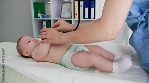 small female child in diapers lies on a diaper table during a doctor examination using phonendoscope in a medical office