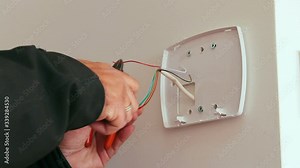 Technician installing or repairing alarm of a smart home security system. Door sensor for burglary prevention. Close up low angle on his hand.