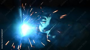 Welder at work. Welding sparkles. Male worker wearing helmet and gloves. Welding metal in factory. Close up of industrial worker at construction site. Man is working.