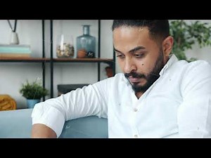 Serious African American man working with laptop computer on couch at home