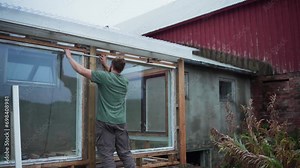 Builder With Foldable Meter Stick Is Measuring Clearance Of Greenhouse Windows. Medium Shot