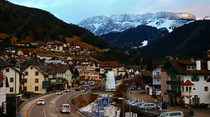 Val Gardena, Italy time-lapse. Evening on the popular winter resort Ortisei of Val Gardena, Italy. Dolomites alps mountains at sunset. Hotels, cafes and restaurants, car traffic lights