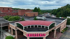 Emergency Entrance at hospital for medical patient and ambulance treatment. Rising aerial reveal.