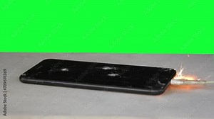 Smartphone on green background ignites from overheating battery, sparks and smoke flying, chromakey.