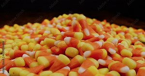 Candy corn falling into pile in slow motion in wide static shot