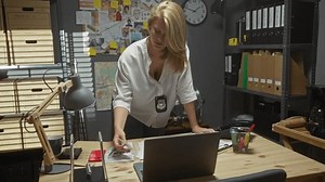 clip-3571995457-focused-blonde-woman-detective-office-environment-examines