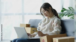 Young Asian woman using laptop to check balance and online shopping enjoy online shopping using credit card.