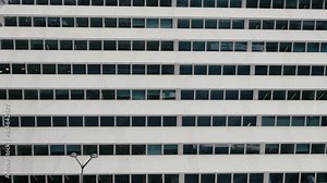 Modern office building facade featuring multiple rows of windows, reflecting a geometric and minimalist architectural design. Modern Building Facade with Geometric Windows in Urban Setting