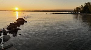 Sunrise swimming long distance on a lake across big body of water with orange sky aerial view