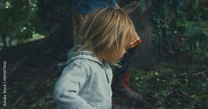 Young mother and toddler foraging in the woods