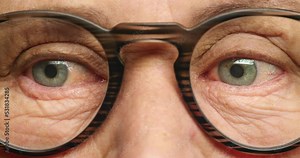 Senior woman face, glasses and eyes for vision, looking around and focus eye care. Zoom macro portrait of elderly grandma, retirement and medical eye care frame, optometry clinic test and human sight