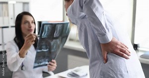 Doctor examines X-ray of patient with spinal pain. Diagnosing causes of back pain concept