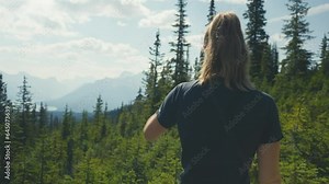 A person are hiking the in the woods, overlooking the stunning view of the Maligne Lake in the Canadien mountains on a clear blue sunny day. Hiking at the Bald Hills Trail in Canada
