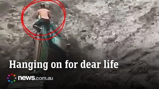 Worker climbs onto excavator to escape raging flood