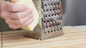 Slow motion of chef grating traditional parmesan cheese with steel grater on the wooden board
