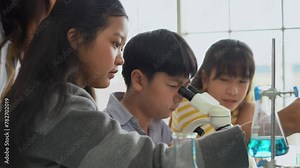 group of asian school kid pupil student looking through microscope together during science practical class in school laboratory. asia children scientists learning biology chemistry lesson .
