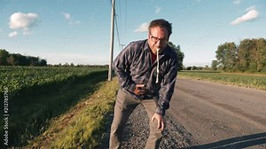 Sick man trowing up on the side of the road vomiting on the ground.