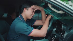 Download Close-up of a man parking his car, bending over the steering wheel of his car, he had an accident in the distance and was upset while waiting for his car insurance to come pick him up. for free