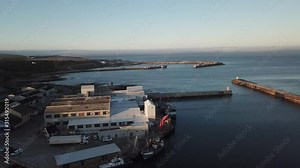 4K summer sunny morning aerial drone video of commercial harbour piers with vessels boats, fishing factory, town panorama, Indian Ocean coast town Gans Bay, Garden Route, Western Cape, South Africa