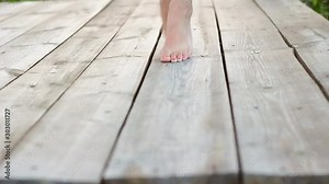 Close up bare feet of girl walking on tiptoes on old wooden floor outdoors