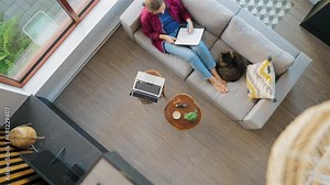 Overhead view of woman writing notes, lying on couch at home