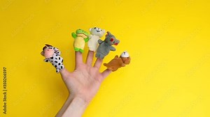 Puppet theater doll animals. Hand wearing finger puppets: cow, frog, dog, rabbit, mouse, bear. animal finger puppets show isolated on yellow background. family quarantine fun. template mock up.