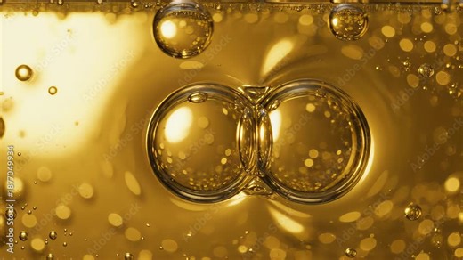 Two large, shimmering bubbles rising through a viscous golden liquid and merging on the surface. Tiny air bubbles float around, creating a sparkling and satisfying effect. asmr,