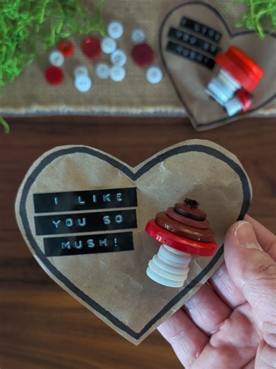 Button Mushroom Valentine 🍄 I was inspired by @Little Pine Learners crayon mushroom valentine to make these button mushroom valentines! To make these mushrooms, fold a pipe cleaner in half and thread on white buttons for the base. Then thread on 4 red buttons starting with the largest button and ending with the smallest. Twist the top of the pipe cleaner and trim off any excess. We glued our mushrooms to a packing paper heart that says
