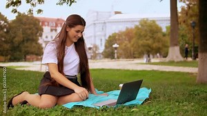 smiling lady use internet for call cheerful girl using laptop sitting on lawn in park