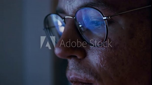 Close-up of disabled programmer coding at night with the code reflecting in his glasses