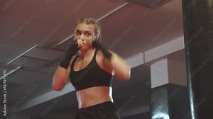 Woman power, female fighter trains his punches and defense in the boxing gym, female trains a series of punches, front view.