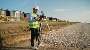 Surveyor engineer using theodolite measuring construction site