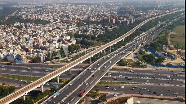 Timelapse view of Indian capital and metropolitan city of New Delhi, India. Drone shot of cars moving on flyover bridges parallel to metro rail station. Roads of developing India.